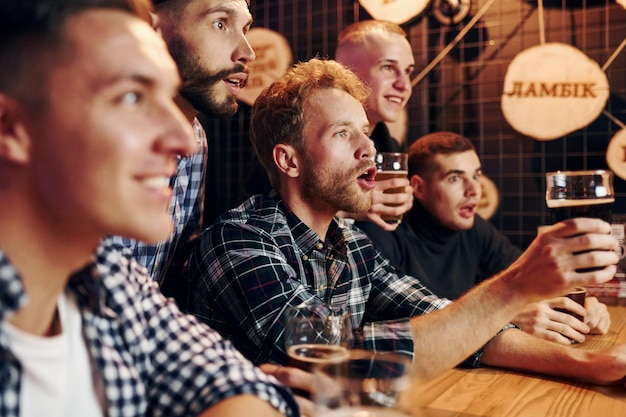 Fans jubeln und schreien Eine Gruppe von Menschen drinnen im Pub hat am Wochenende Spaß