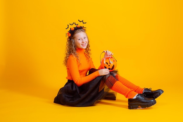 fantasia de bruxa adolescente em fundo amarelo segurando vermes de marmelada de abóbora confent halloween
