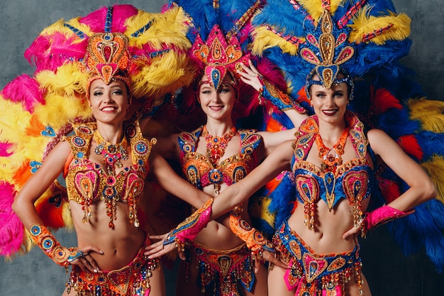 Fantasia de três mulheres no samba brasileiro de carnaval com plumagem de penas coloridas