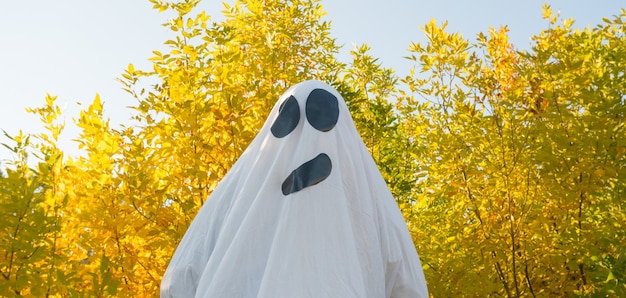 Fantasma de Halloween bailando en el bosque de otoño amarillo agitando sus manos