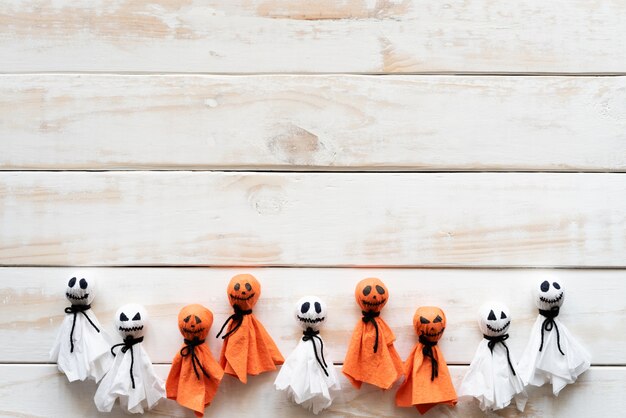 Fantasma de papel blanco y anaranjado en el fondo de madera blanco, concepto de Halloween.