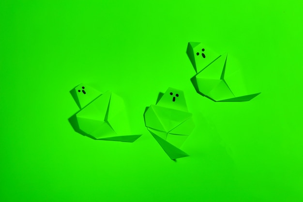 Fantasmas de origami en luz de neón verde. Tema de halloween
