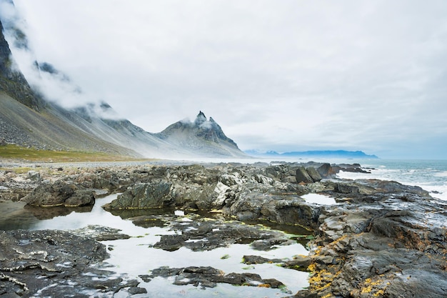 Fantástica costa del océano Atlántico con piedras volcánicas y vista a la montaña. Sur de islandia