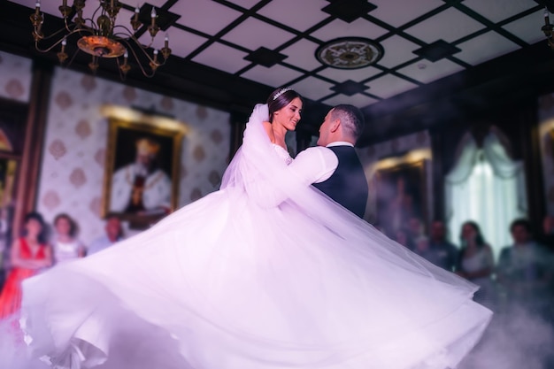 Fantástica pareja de novios bailando su primer baile en un restaurante hombre rodeando a la novia en sus brazos