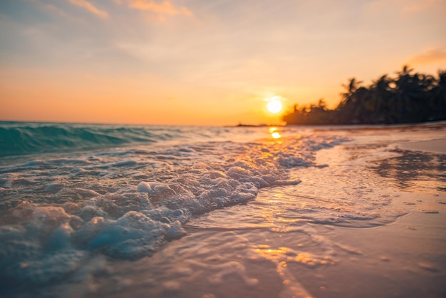 Fantástica vista de primer plano de las tranquilas olas del mar con la luz del sol naranja del amanecer. Isla tropical