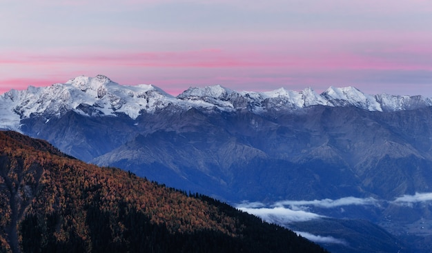 Fantásticas montanhas cobertas de neve nas belas nuvens cumulus.