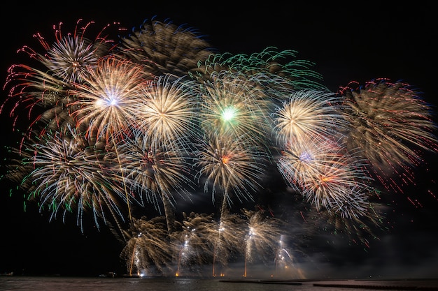 Fantástico fogo de artifício multicolor explodindo para celebração do grande barco sobre o mar