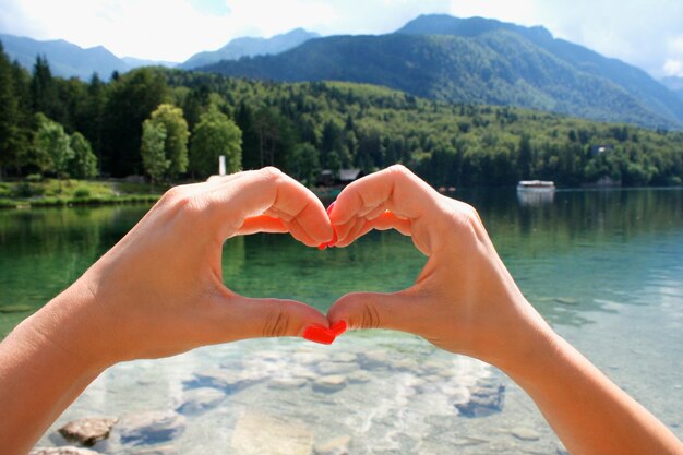 Fantástico lago de montanha no parque nacional de Triglav com garota que mostra o coração da mão