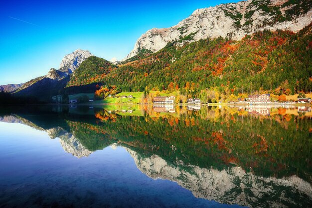 Fantástico nascer do sol do outono do reflexo do espelho do lago Hintersee