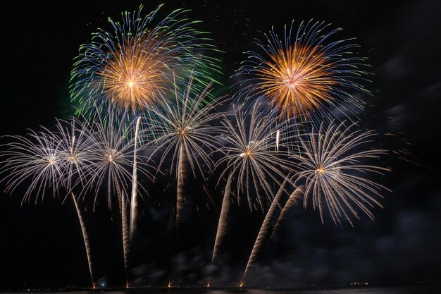 Fantásticos fuegos artificiales multicolores explotando para la celebración desde el gran barco sobre el mar