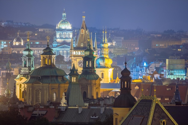 Fantásticos techos de la ciudad vieja de Praga durante el crepúsculo con torres de reloj e iluminación nocturna República Checa Monumento famoso europeo