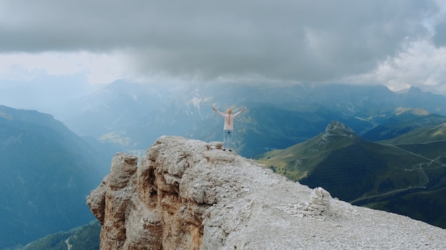 Fantastische Landschaft von Bergfelsen und Frau, die oben mit ausgestreckten Händen steht