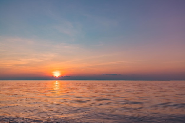 Fantastische Nahaufnahme von ruhigen Meerwasserwellen mit orangefarbenem Sonnenaufgang und Sonnenuntergang. Tropische Insel