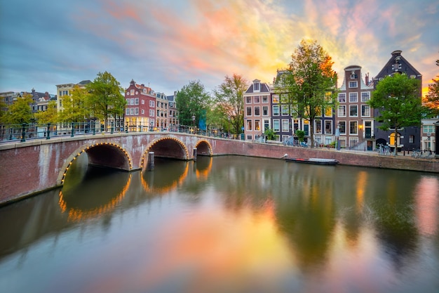 Fantastischer Sonnenuntergang Sonnenuntergang Sonnenaufgang Farben in Amsterdam Panoramablick auf die berühmten alten Häuser, die Brücke und den Kanal in der Innenstadt von Amsterdam Holland Niederlande Europa