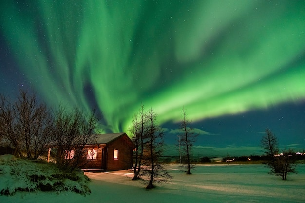 Fantastisches Nordlicht über einem schönen Häuschen, das vom Schnee bedeckt wird