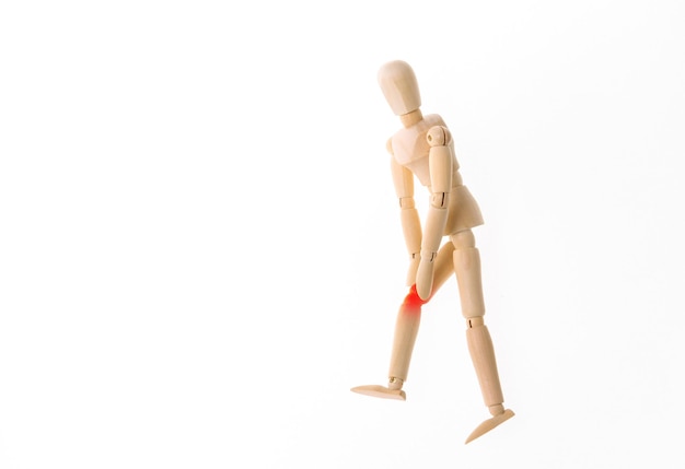 Fantoche de madeira com dor nas pernas, isolado no fundo branco. Osteoartrite