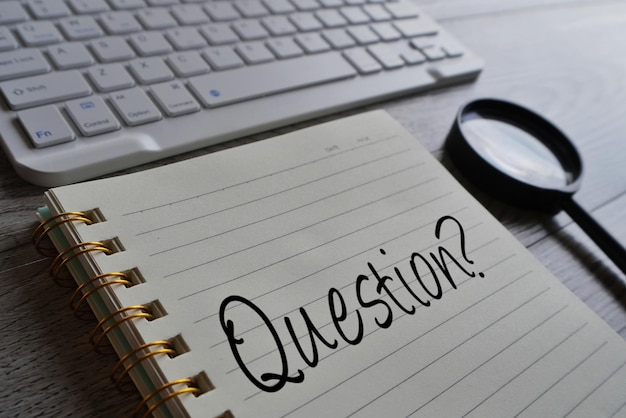 FAQ-Fragen und Antworten zum Hintergrundkonzept Nahaufnahme einer Tastaturlupe und eines Notizbuchs mit dem Wort „Frage“.