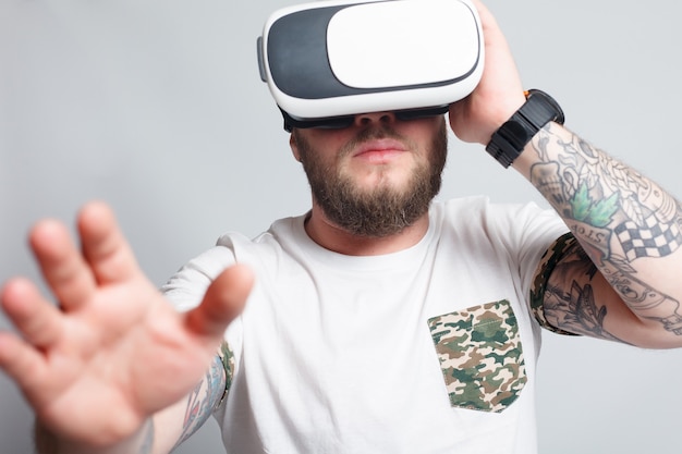 Farbaufnahme eines jungen Mannes, der durch eine virtuelle Realität schaut, ein Gerät, mit dem man virtuelle Realität auf einem Mobiltelefon erleben kann. Mann berührt die Hand. verschwommene Fotos