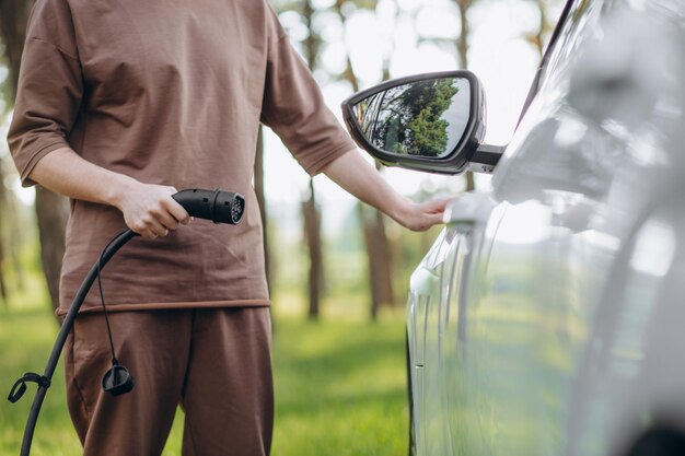 Farbbild der Hand eines Mannes, der sich darauf vorbereitet, ein Elektroauto aufzuladen