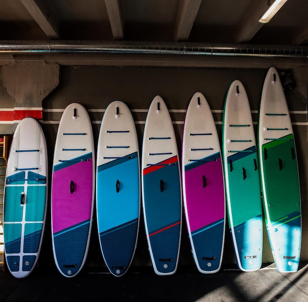 Foto farbenfrohe aufblasbare standup-paddle-boards sup an der wand surfen und sup-boarding-ausrüstung aus der nähe