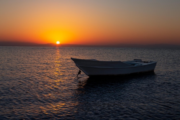 Farbenfroher Sonnenaufgang mit einem Fischerboot im Vordergrund Dahab Sinai Ägypten