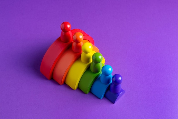 Farbenfroher Waldorf-Holzfigurenregenbogen in einer Montessori-Lehrpädagogik auf violettem Hintergrund Kinderspielkonzept