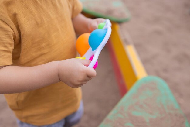 Farbenfrohes, trendiges Anti-Stress-Sensorspielzeug, Fidget-Push-Pop-It und einfaches Grübchen in Kinderhänden, Kinder teilen Spielzeug und spielen zusammen