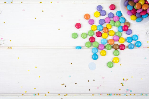 Farbige Bonbonbonbons verstreut auf weißer Holzbrettoberfläche Studiofoto