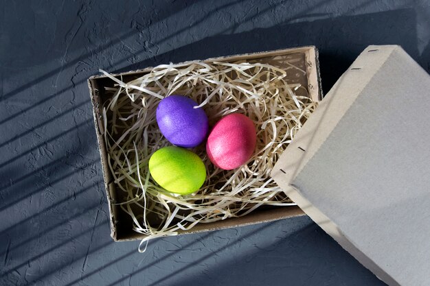 Farbige Eier in einer Box auf einer schwarzen Wand, Ansicht einer Draufsicht. Osterkonzept.