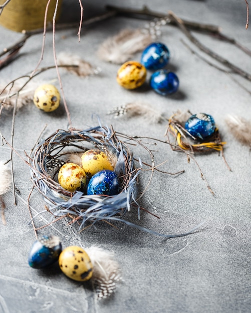 Farbige gelbe und blaue Ostern Wachteleier in kleinen Nestern. Wachteleier für katholische und orthodoxe Osterfeiertage.