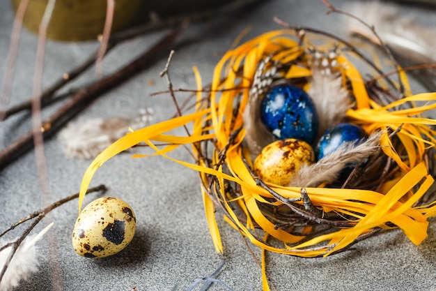 Farbige gelbe und blaue Osterwachteleier in kleinen Nestern. Wachteleier für katholische und orthodoxe Osterferien. Geringe Schärfentiefe.