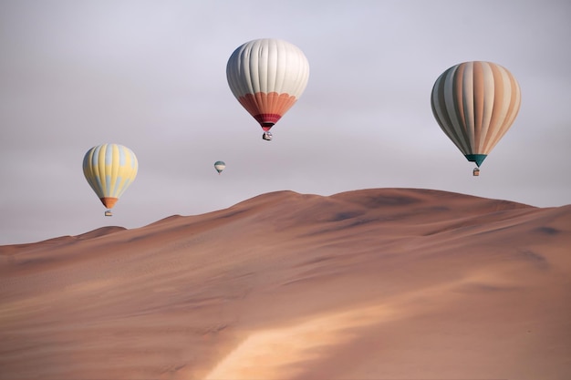 Farbige Heißluftballons, die bei Sonnenuntergang über die Sanddünen fliegen Afrika Namibia Schönheitswelt