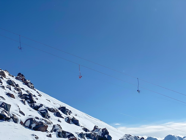Farbige Sitze der Skilift in den Bergen auf einem blauen Himmel Hintergrund Transport zur Spitze