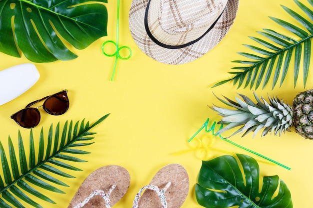 Farbige Sommerkomposition mit Strohhut, Sonnenbrille, Palmblättern, Ananas und Flip-Flops