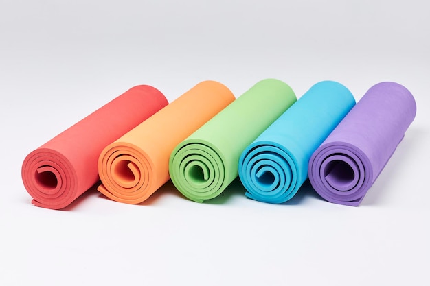 Farbige Yoga-Matten auf weißem Hintergrund Übungsmatten auf dem weißen Hintergrund isoliert