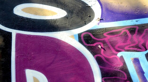 Farbiger Hintergrund von Graffiti-Malerkunstwerken mit hellen Aerosol-Umrissen an der Wand der alten Schule