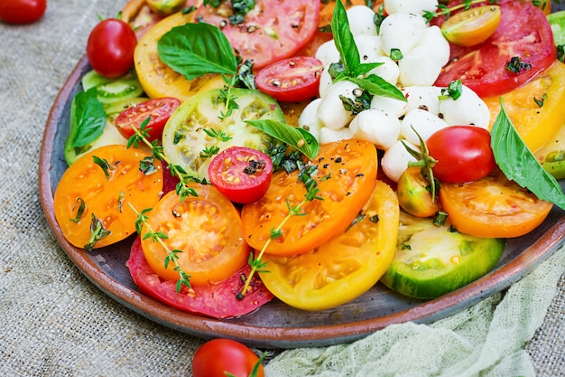 Farbiger Tomatensalat mit Käsemozzarella und Basilikum. Capresesalat. Veganes Essen.