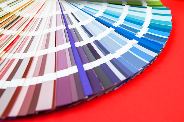 Farbleitfaden Nahaufnahme Blumensortiment für Design Farbpalettenfächer auf rotem Hintergrund Ein Grafikdesigner wählt Farben aus einem Farbpalettenleitfaden aus Farbmusterkatalog