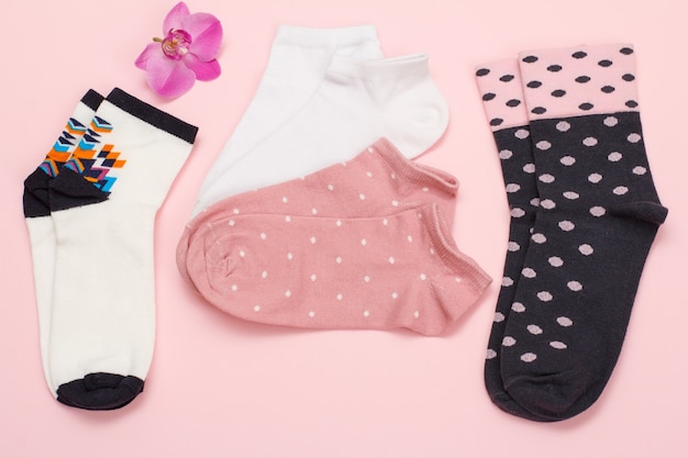 Farbpaare Damensocken und Orchideenblüte auf rosa Hintergrund, Ansicht von oben.