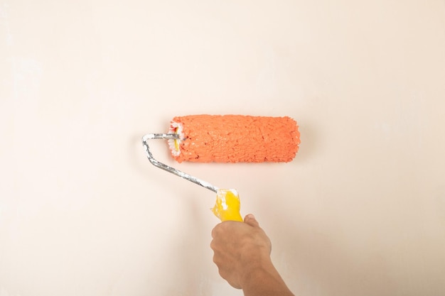 Farbroller in der Hand des Arbeiters auf dem Hintergrund der Wand