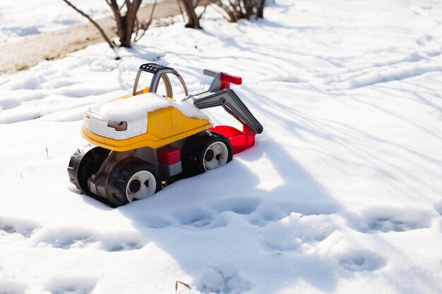 Farbspielzeugbagger im Winter. Konzept zu Bettwetter und Schneeräumung