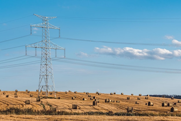 Fardos de paja en el campo cerca de altas torres de alta tensión