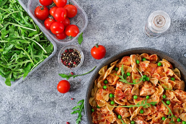 Farfalle macarrão com filé de frango, molho de tomate e ervilhas verdes. Comida caseira. Cozinha italiana. Menu de comida. Vista do topo