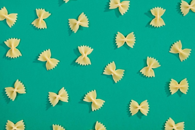 Farfalle-Pasta mit zufälligem flachem Muster auf grünem Hintergrund