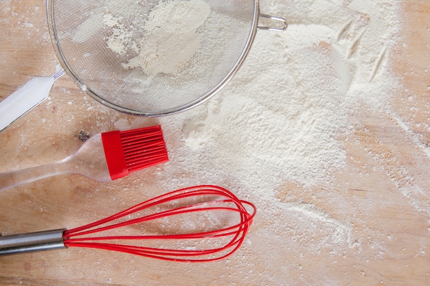 Farinha branca e ferramentas de silicone vermelho na tábua de madeira