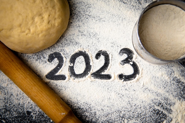 Farinha de cozimento e número 2023 no quadro-negro Vista superior Fundo alimentar de ornamento de ano novo Feito em casa