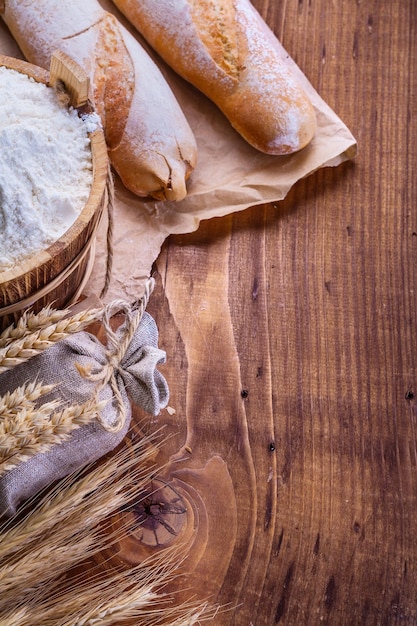 Farinha de pão no balde e espigas de trigo em tábuas de madeira velhas