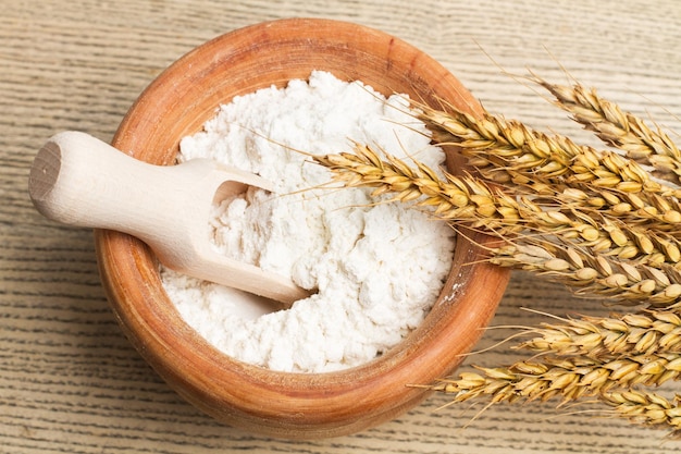 Farinha em uma tigela de madeira com uma colher de pau em uma mesa de madeira