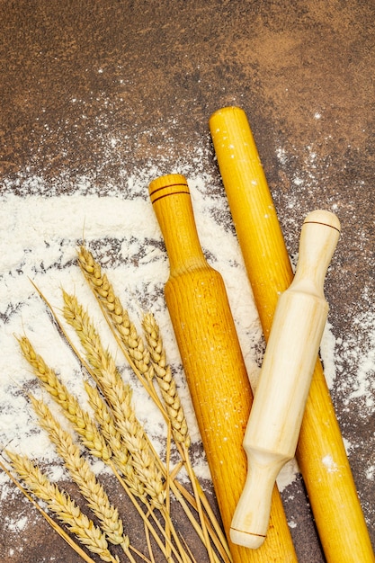 Farinha espalhada, espigas de grão e rolos de madeira. Conceito de panificação, close up