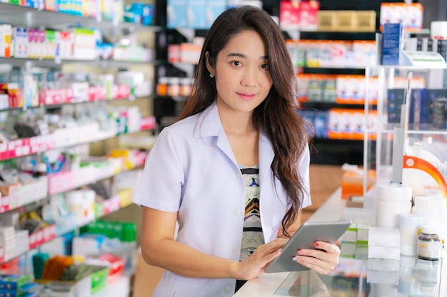 Farmacéutica asiática utiliza tableta digital en la farmacia